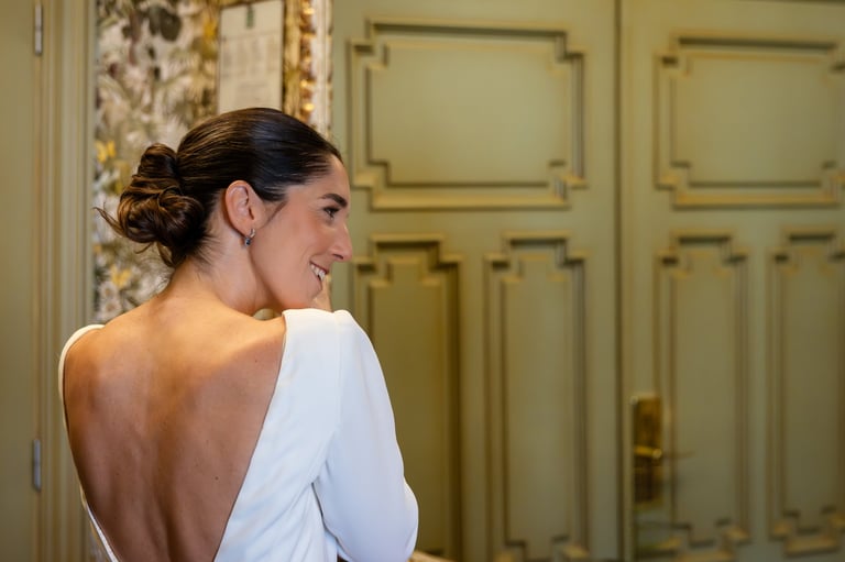 Happy bride showing her backless wedding dress and updo hairstyle looking back and smiling