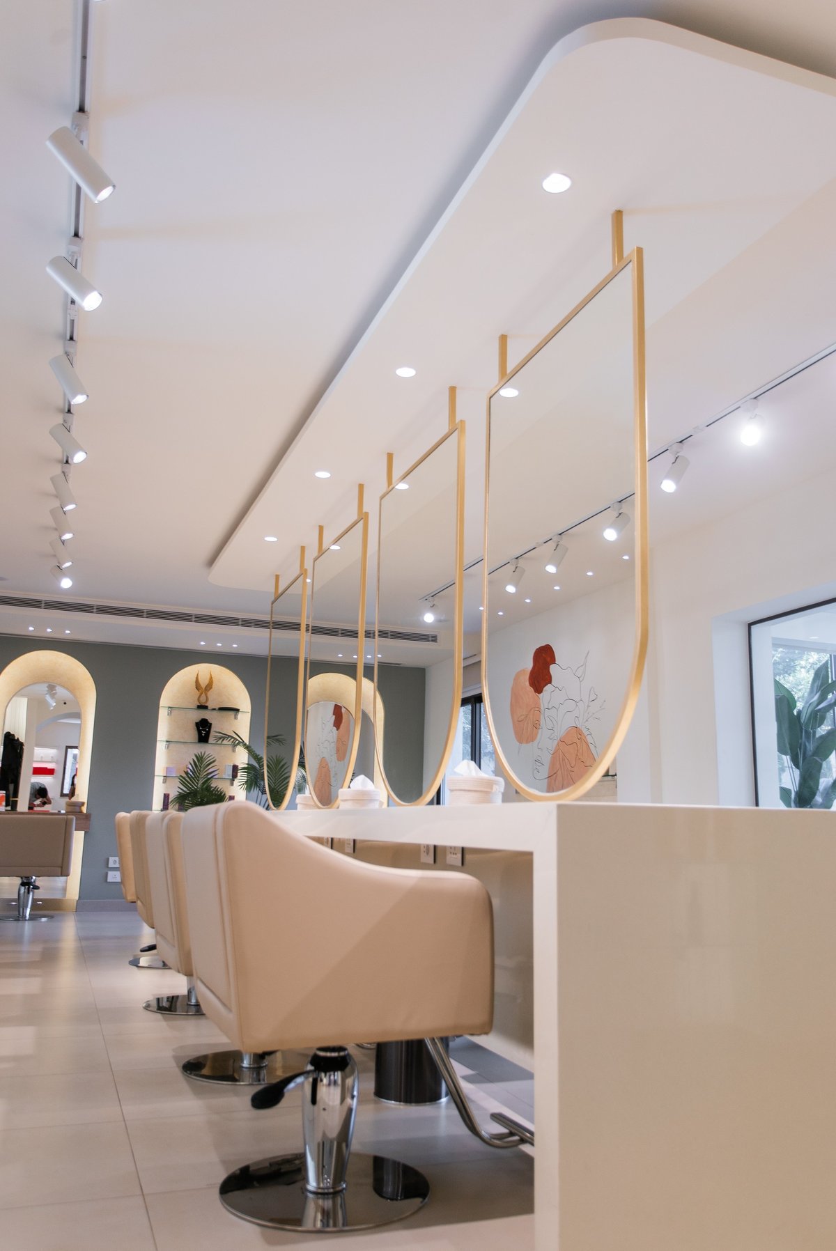 Modern hair salon interior with white styling stations and wooden pendant mirrors